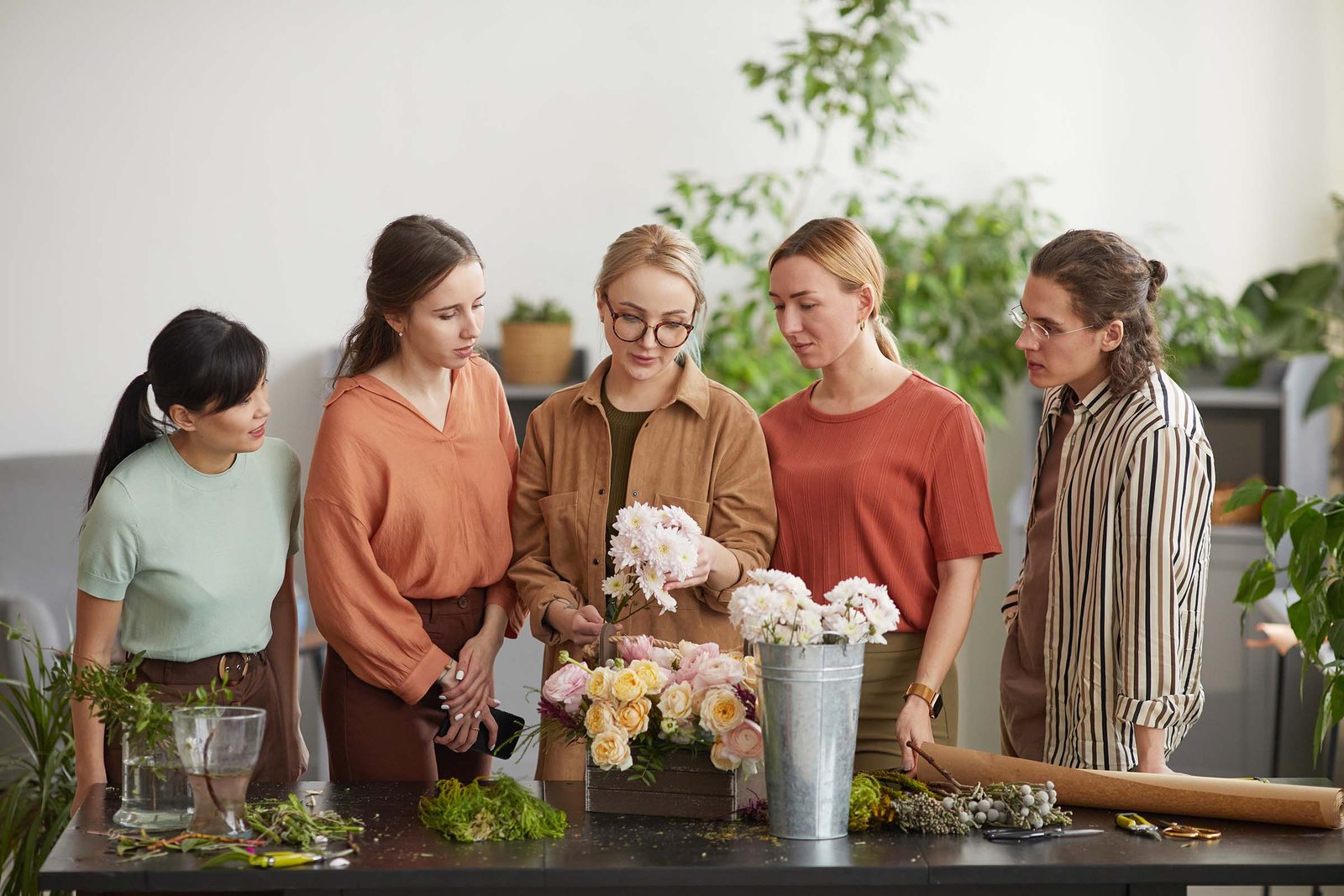Gruppe bindet gemeinsam Blumen an einem gro&szlig;en Werktisch