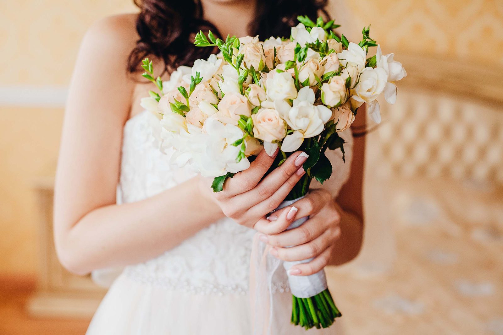 Braut h&auml;lt einen zarten Brautstrau&szlig; aus wei&szlig;en Callas und Rosen